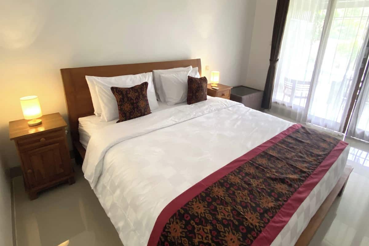 A hotel room with a large bed, two bedside tables, and a nightstand.