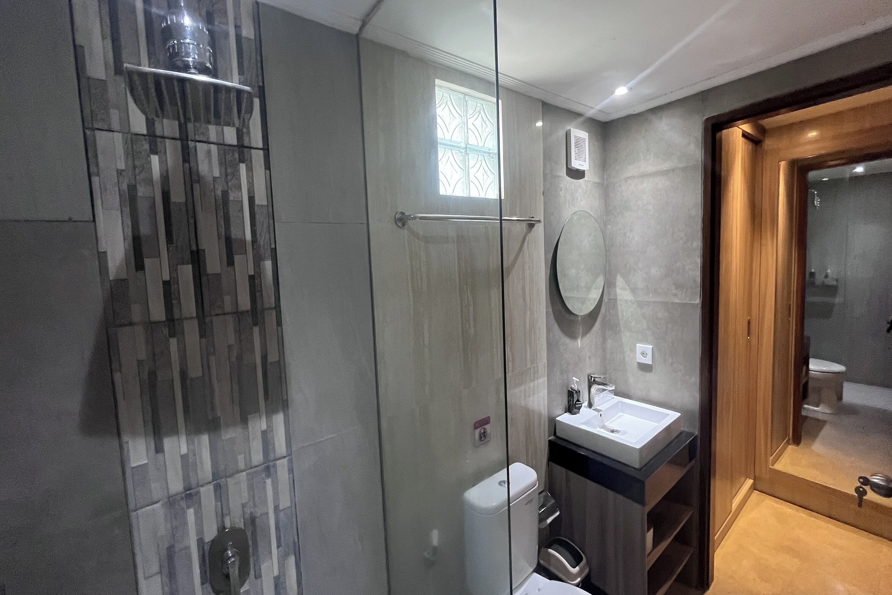 A modern bathroom with a glass shower enclosure, a sink with a mirror, and a toilet.