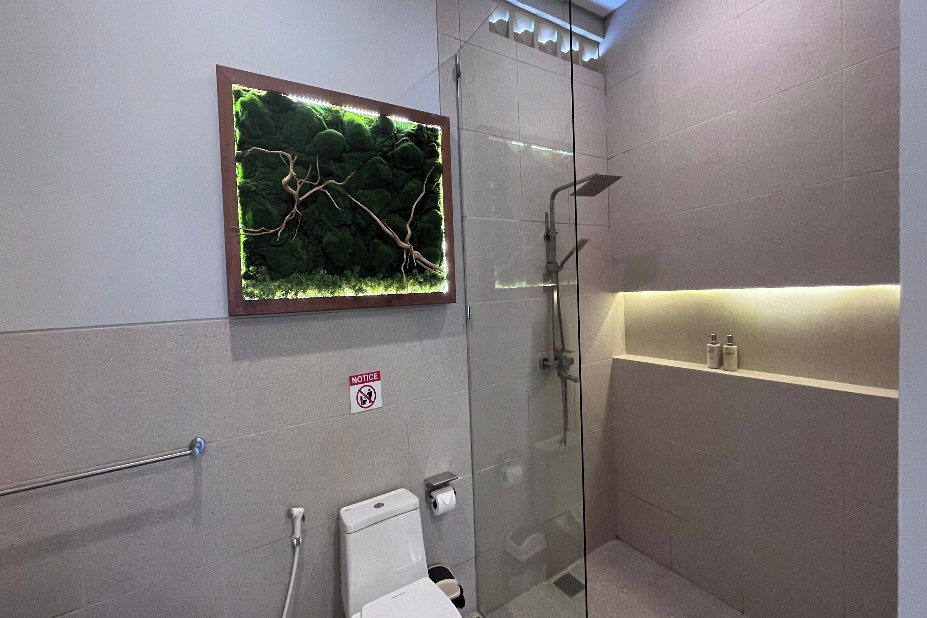 A modern bathroom with a glass shower enclosure, a toilet, a sink with a mirror, and a shelf with toiletries.