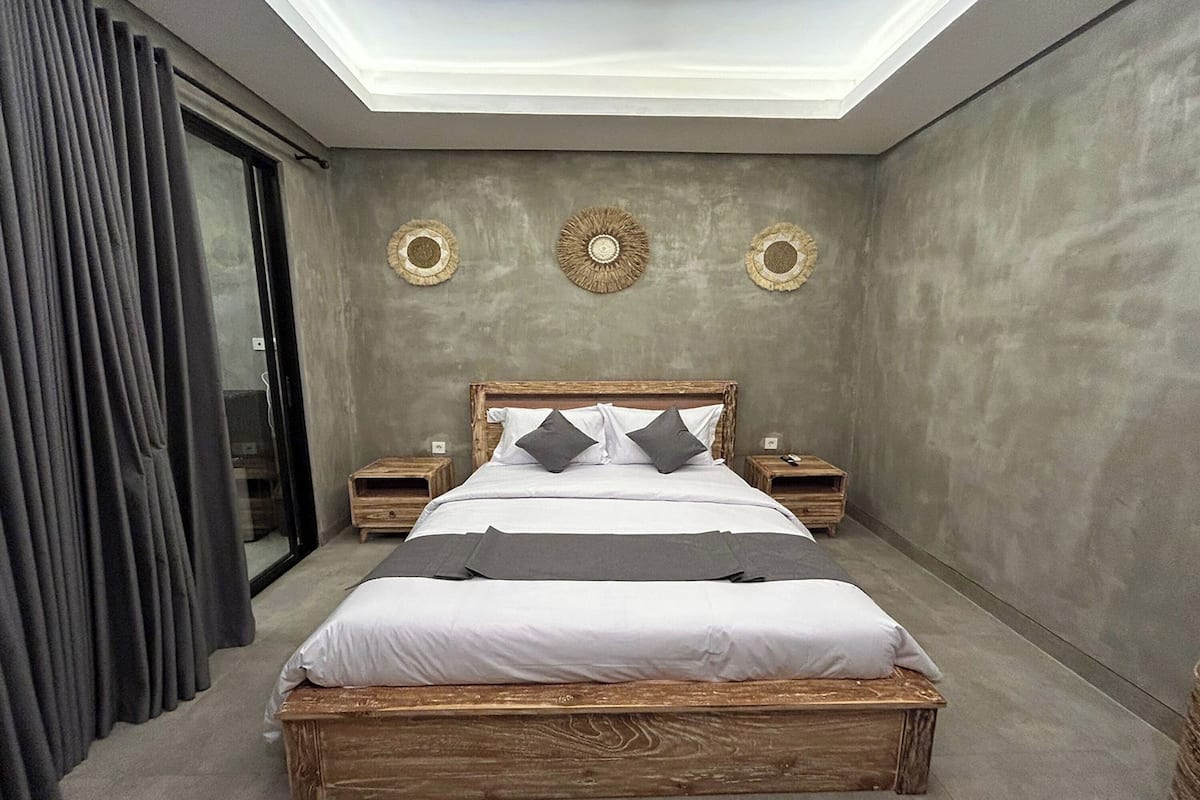 A modern bedroom with a wooden bed, grey bedding, and a skylight.