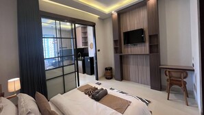 A modern hotel room with a bed, a desk, a TV, and a wardrobe. - Ranala Coliving (Keroboken Kelod)