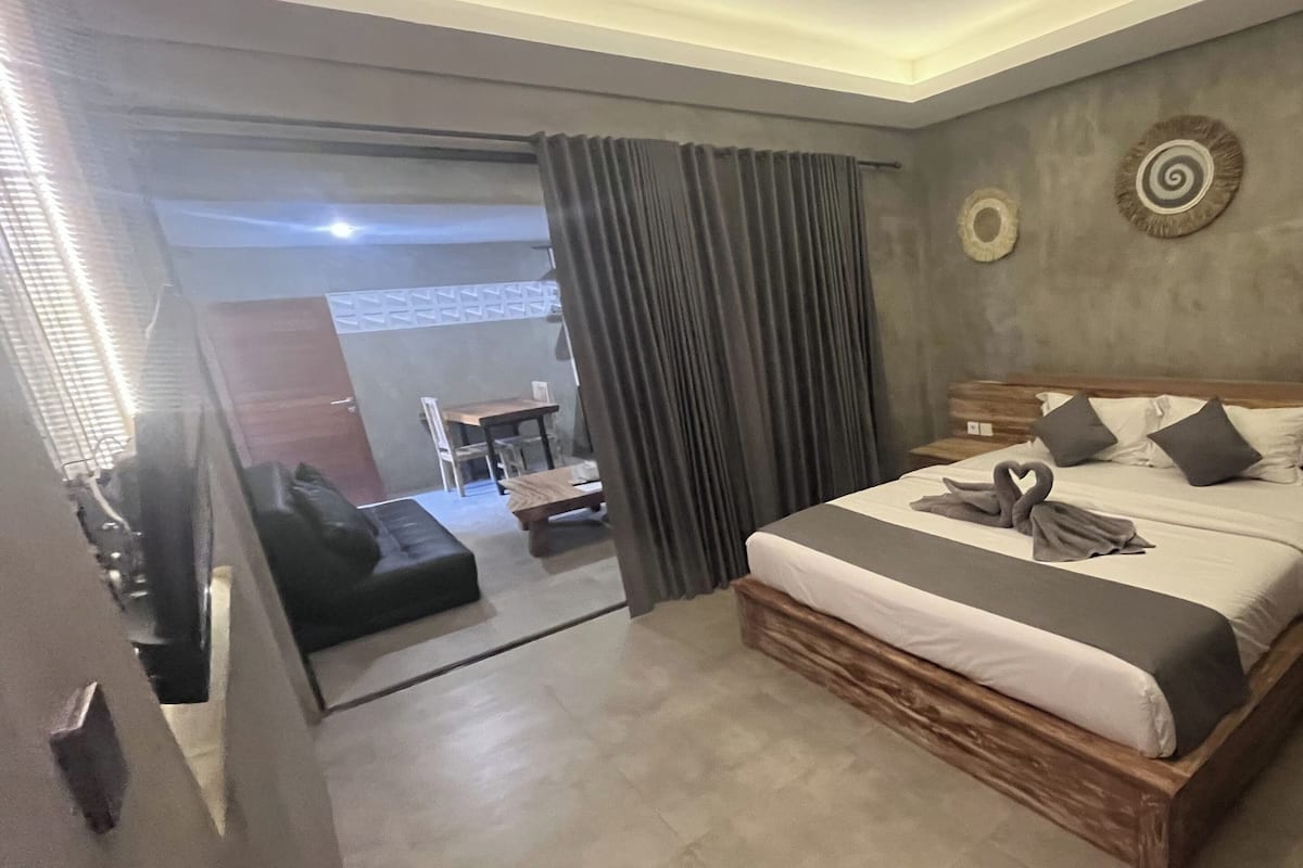 A modern bedroom with a large bed, wooden headboard, and a small bedside table.