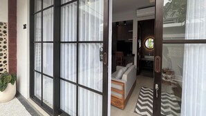 A modern interior with a sliding glass door leading to a living area featuring a sofa and a dining table. - Ranala Coliving (Keroboken Kelod)