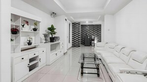 A modern living room with a sofa, a coffee table, and a white entertainment unit with shelves. - TOS Guest House By Zuzu (Jakarta)