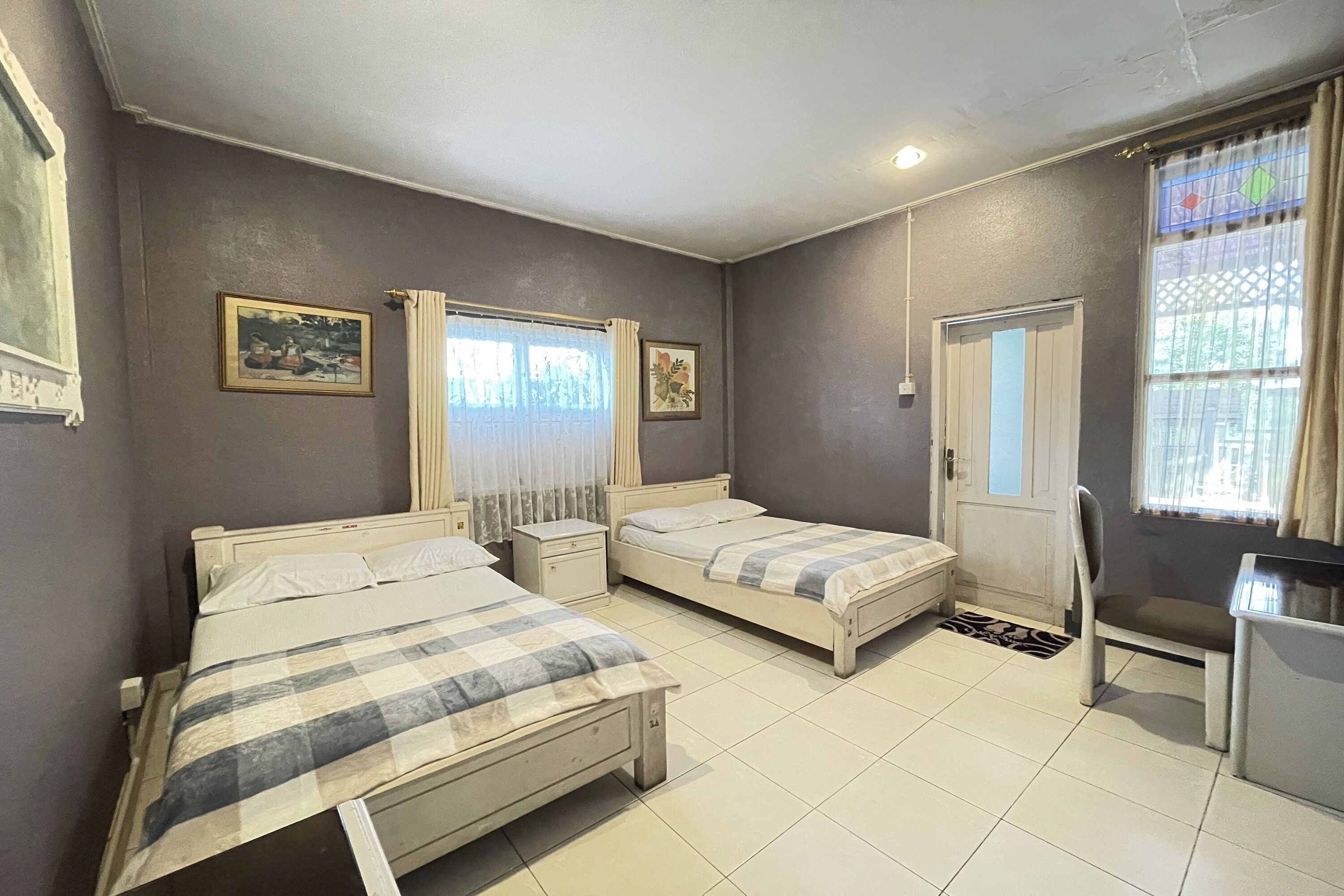 Una habitación con dos camas, una silla, un escritorio y una puerta.