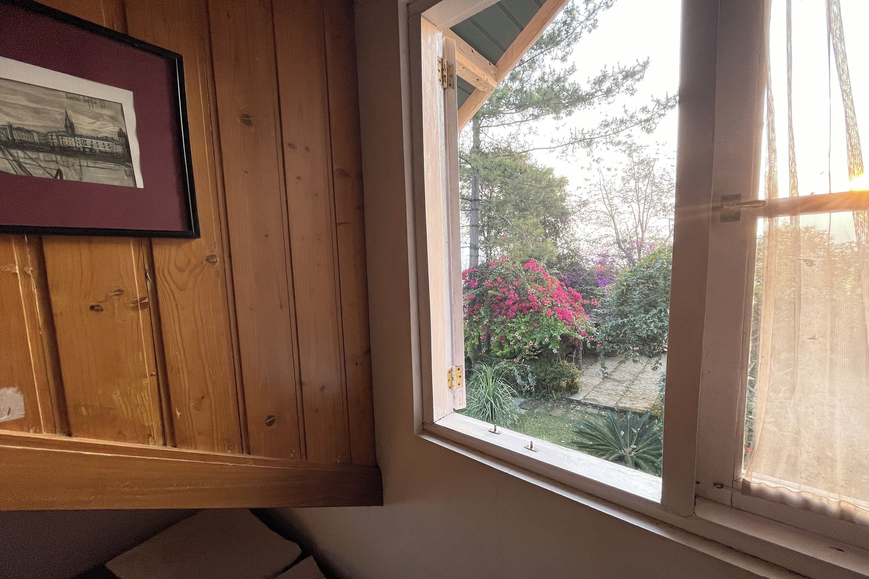 Une pièce aux murs lambrés, avec un tableau encadré et une fenêtre donnant sur un jardin.