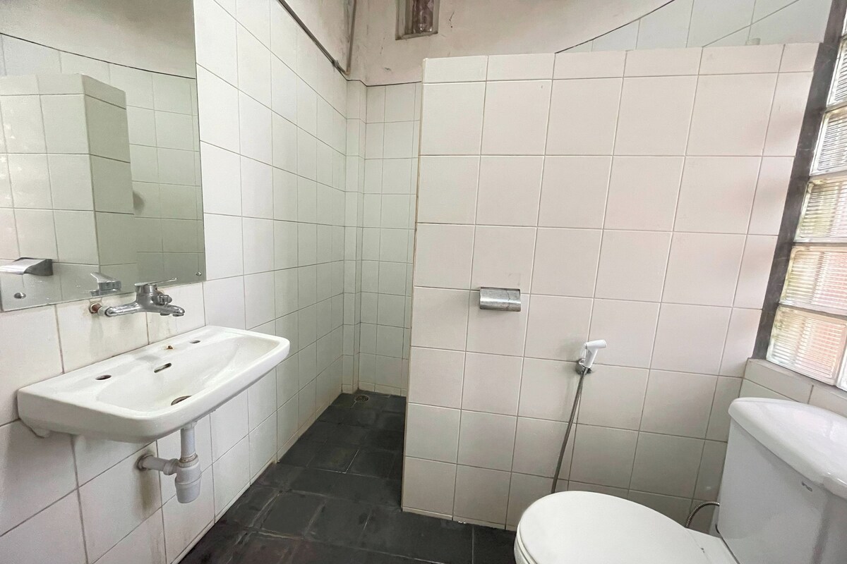 Une salle de bain avec un lavabo blanc, un miroir et des toilettes.