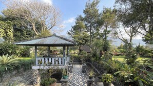A garden with a gazebo, stone pathway, and various potted plants. - Villa 325 By Zuzu (Lembang)