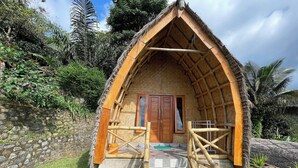 A thatched-roof hut with a wooden door and a small porch area.