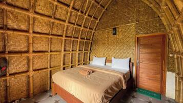 Una habitación con techo de paja, una cama de madera y una puerta de madera.