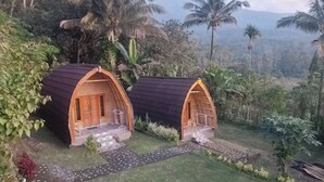 Two small, arched wooden structures with steps leading up to them, surrounded by lush greenery and palm trees. - Villa Bambu Rinjani & Restaurant (Bayan)
