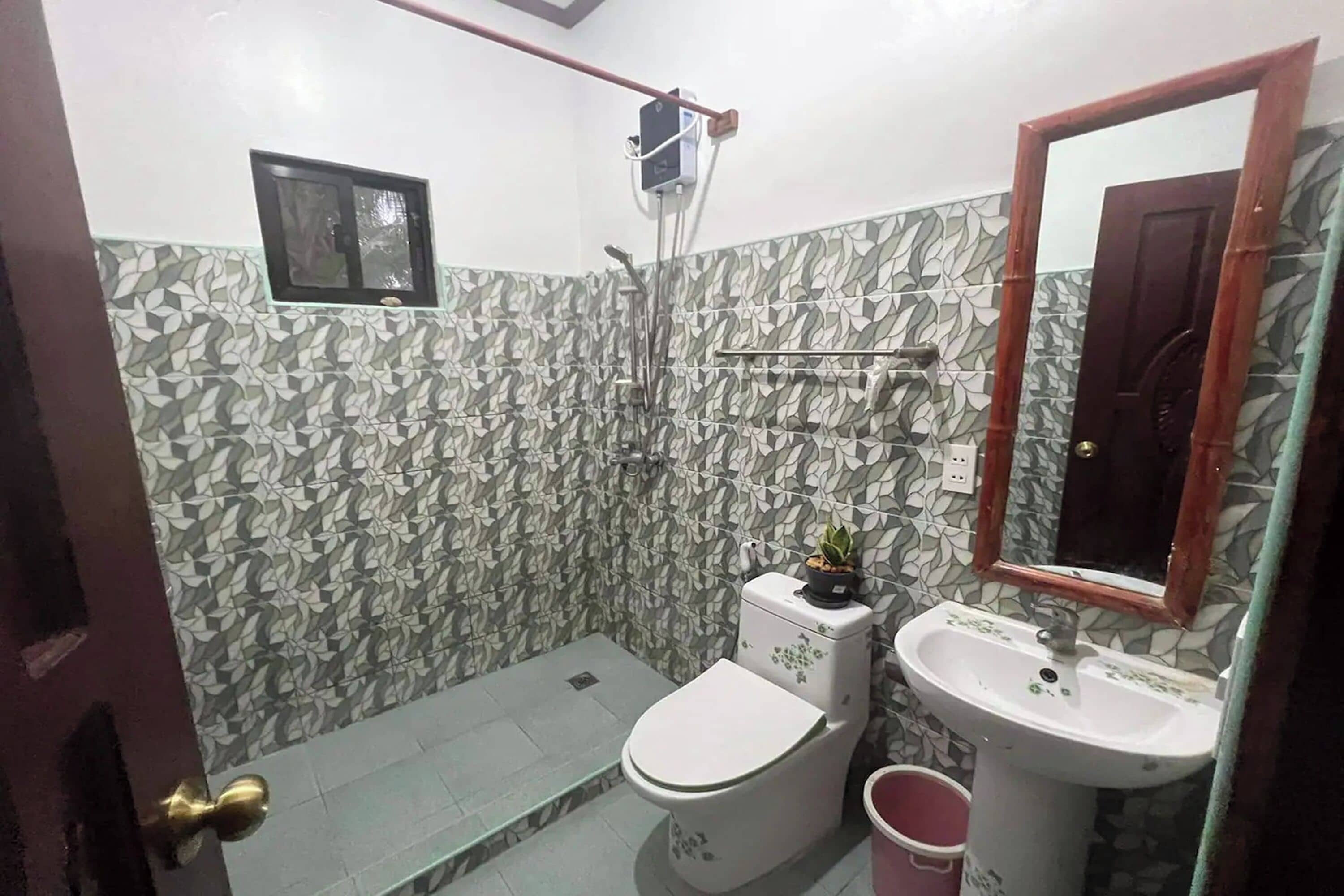 Uma casa de banho com azulejos estampados, sanita, lavatório e chuveiro.