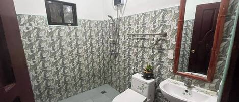 Uma casa de banho com azulejos estampados, sanita, lavatório e chuveiro.