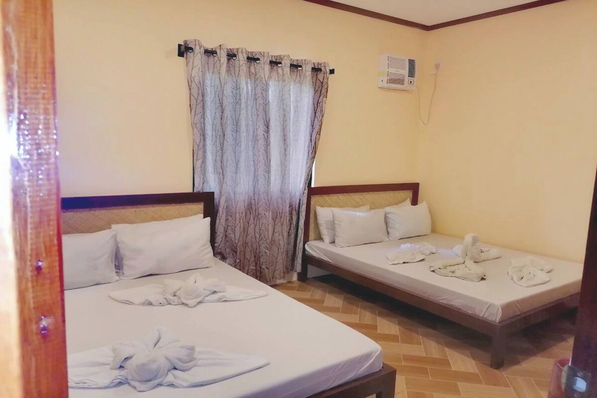 Ein Hotelzimmer mit zwei Betten, einem Vorhang, einer Klimaanlage und Holzboden.