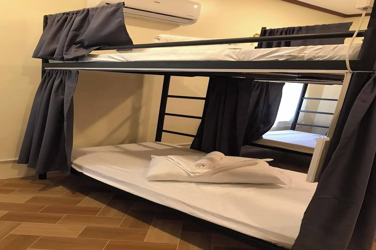 Ein Schlafzimmer mit Etagenbetten, einem Fenster, Vorhängen und einer Klimaanlage.