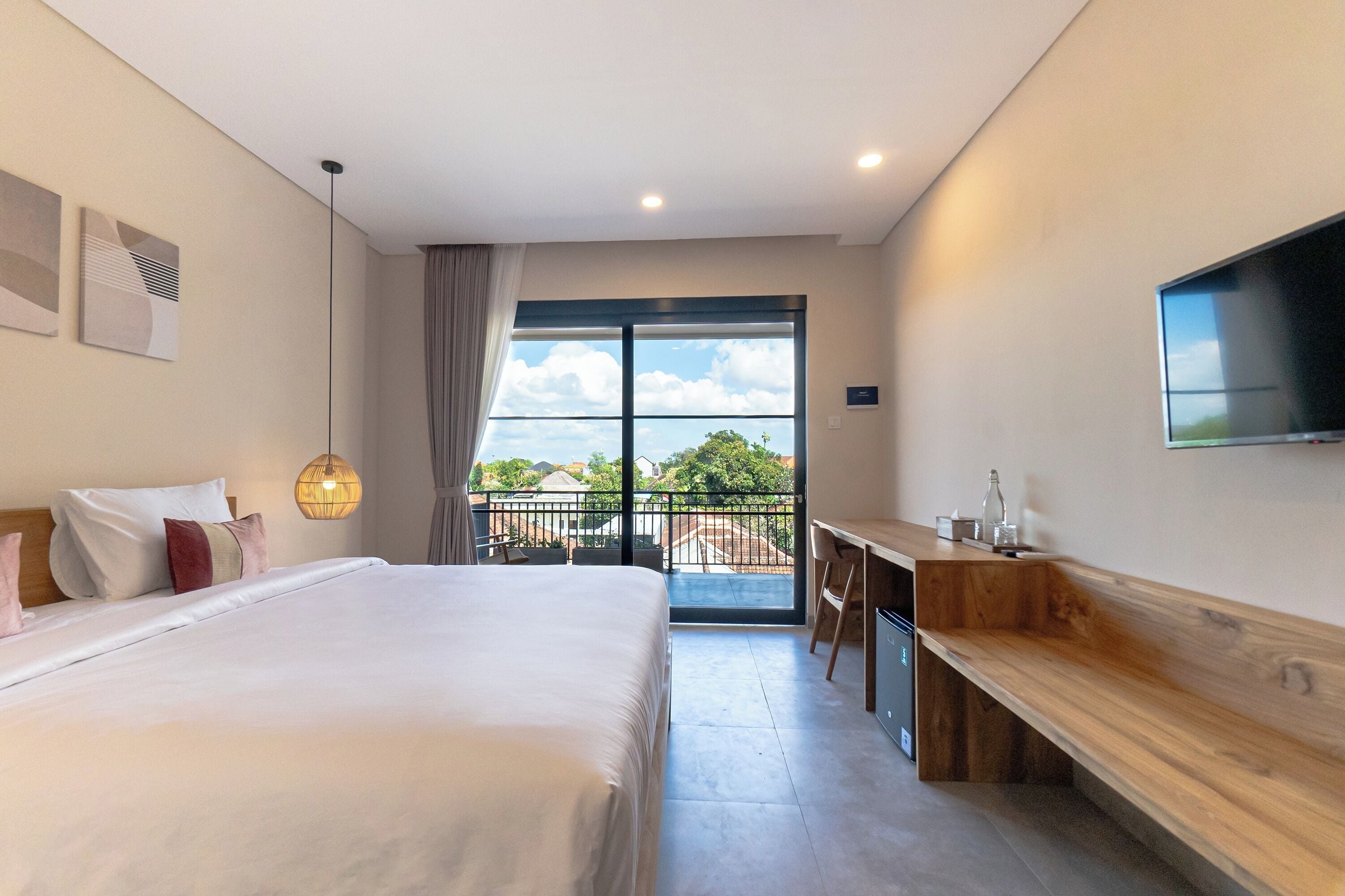 A modern hotel room with a large bed, a desk, and a TV.