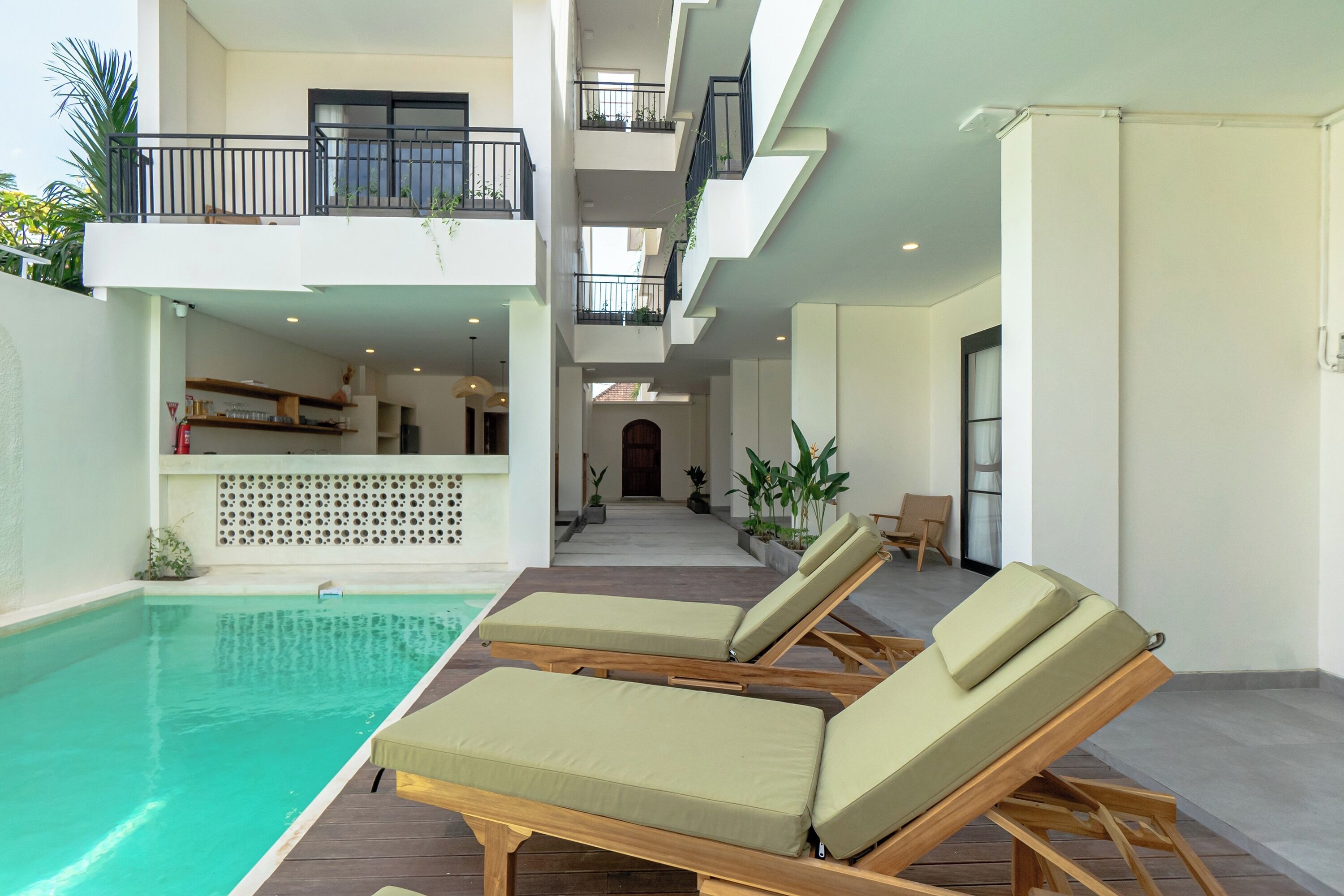 Zona de piscina interior moderna con sillones reclinables y vista al espacio interior.