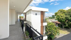 A modern building with a balcony, a clear sky, and surrounding greenery. - Kelaya Guesthouse (Denpasar)