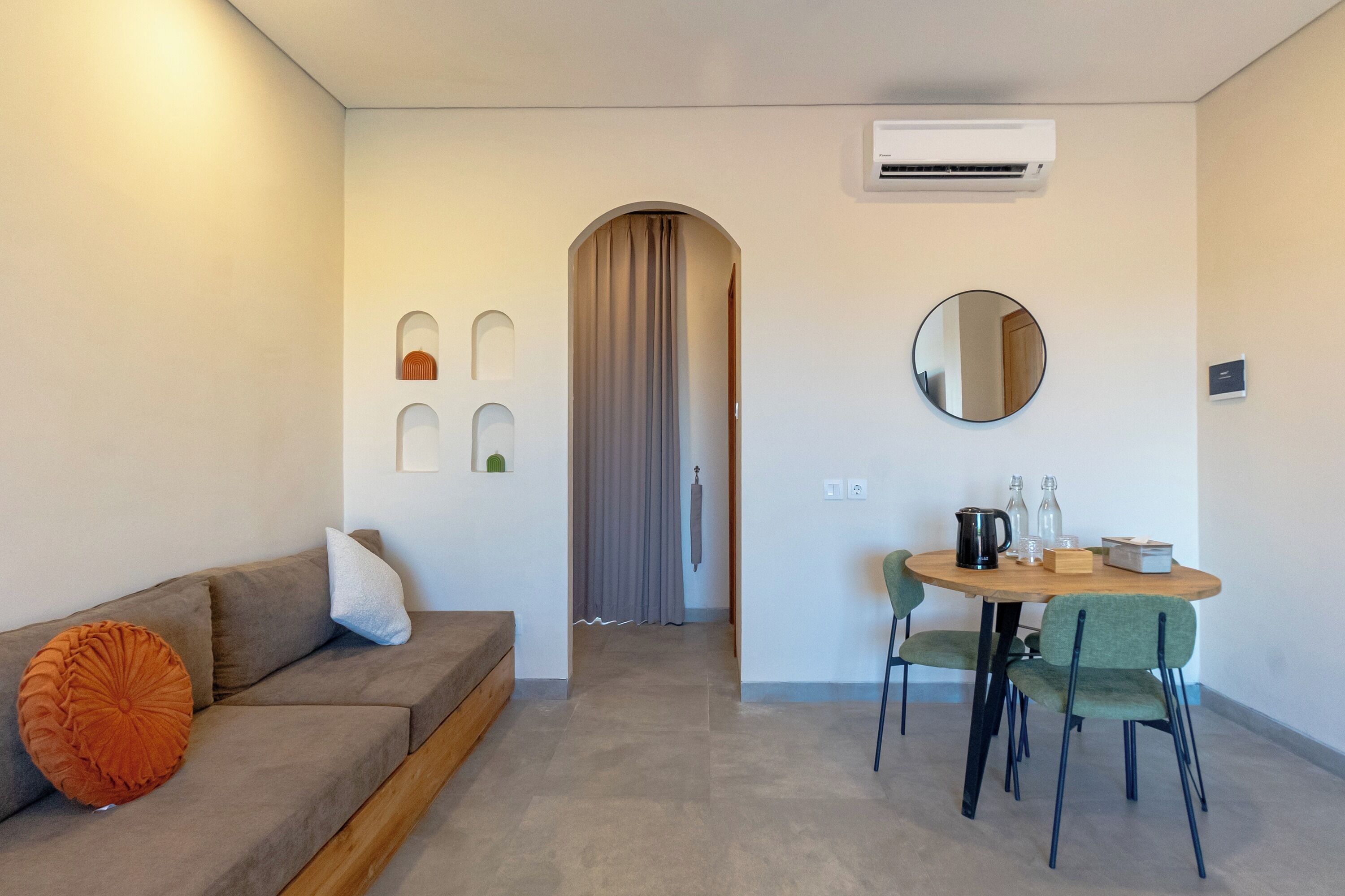 Een moderne woonkamer met een bank, een eettafel met stoelen, een spiegel en een airconditioner.