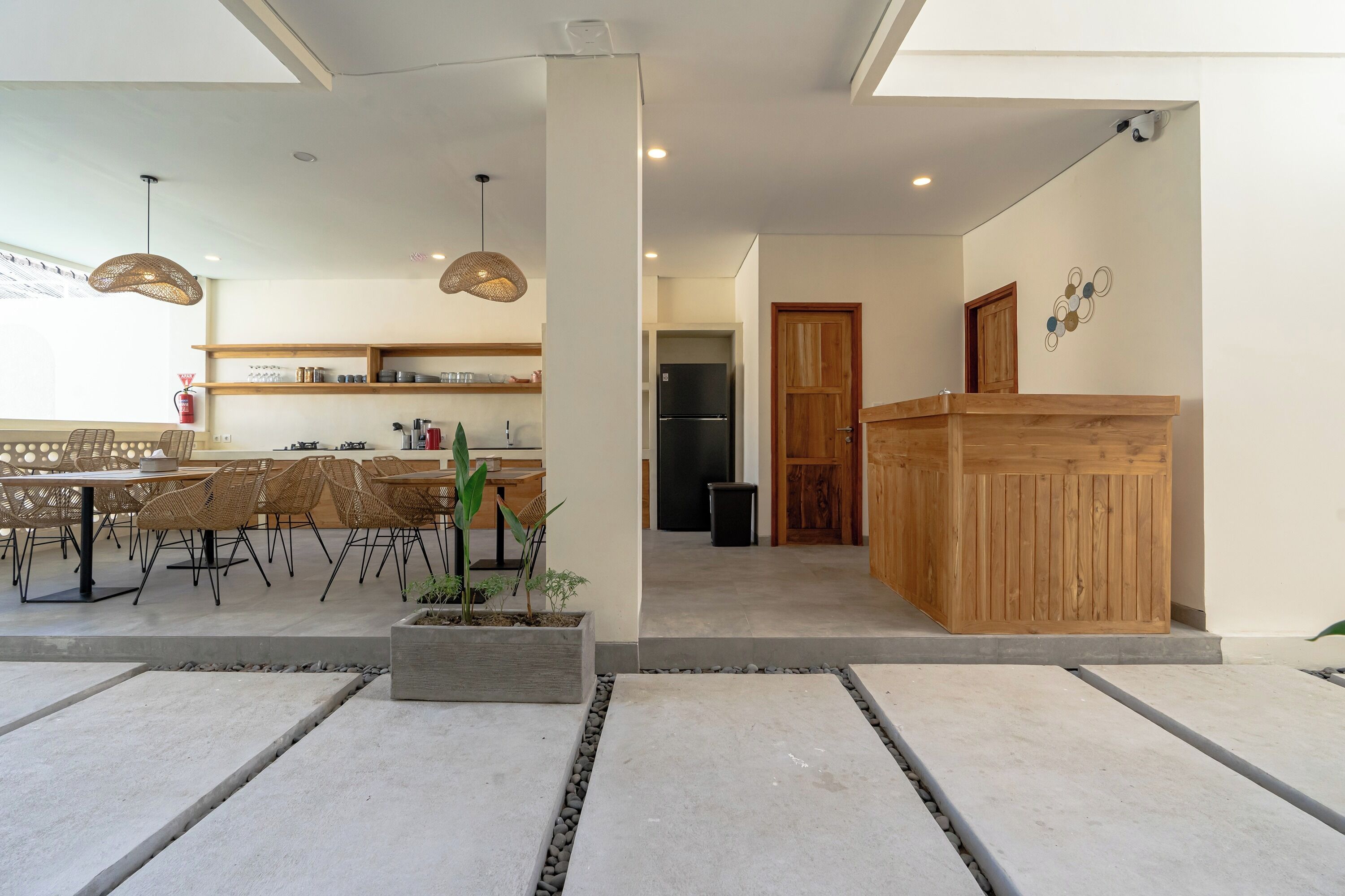 A modern kitchen with wooden cabinets, a built-in refrigerator, and a dining area with wicker chairs and a table.