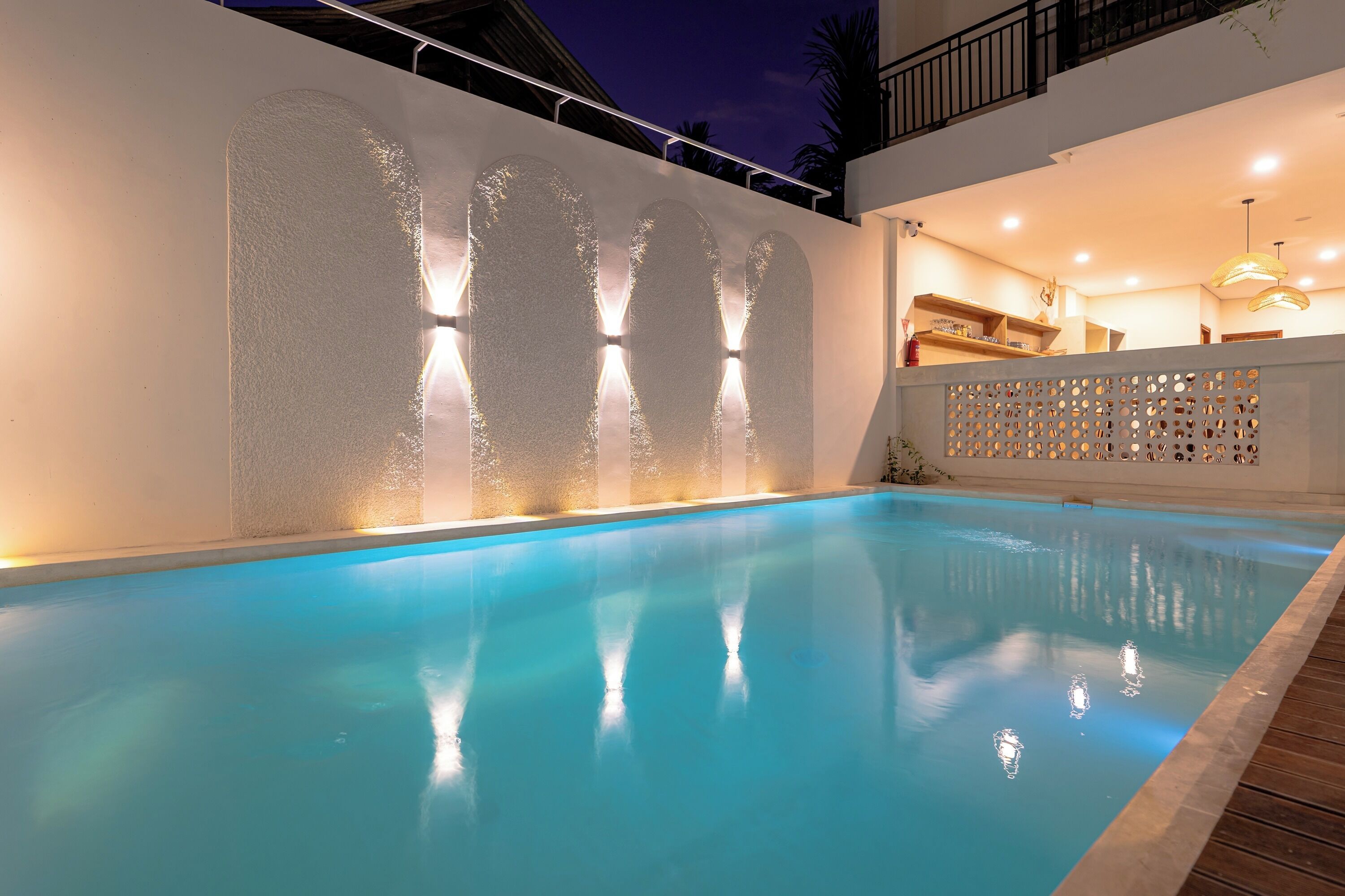 Piscina con pared blanca y diseño texturizado, con iluminación integrada.