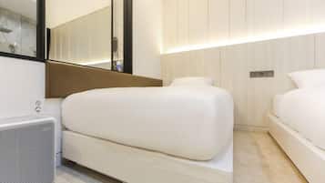 Una habitació d'hotel moderna amb un llit gran, una taula de nit, un mirall i una làmpada de paret.