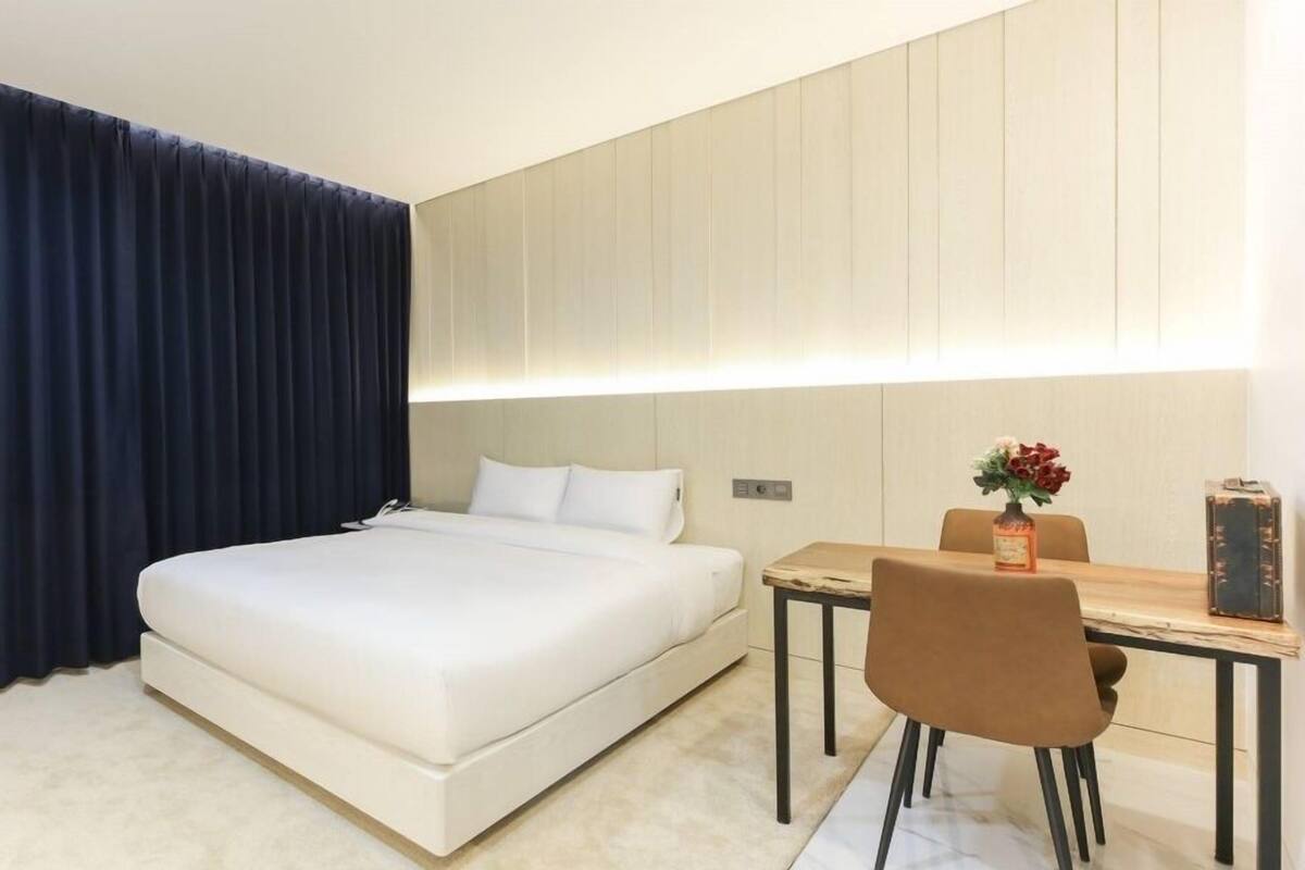 A modern hotel room with a large bed, a desk, and a chair.