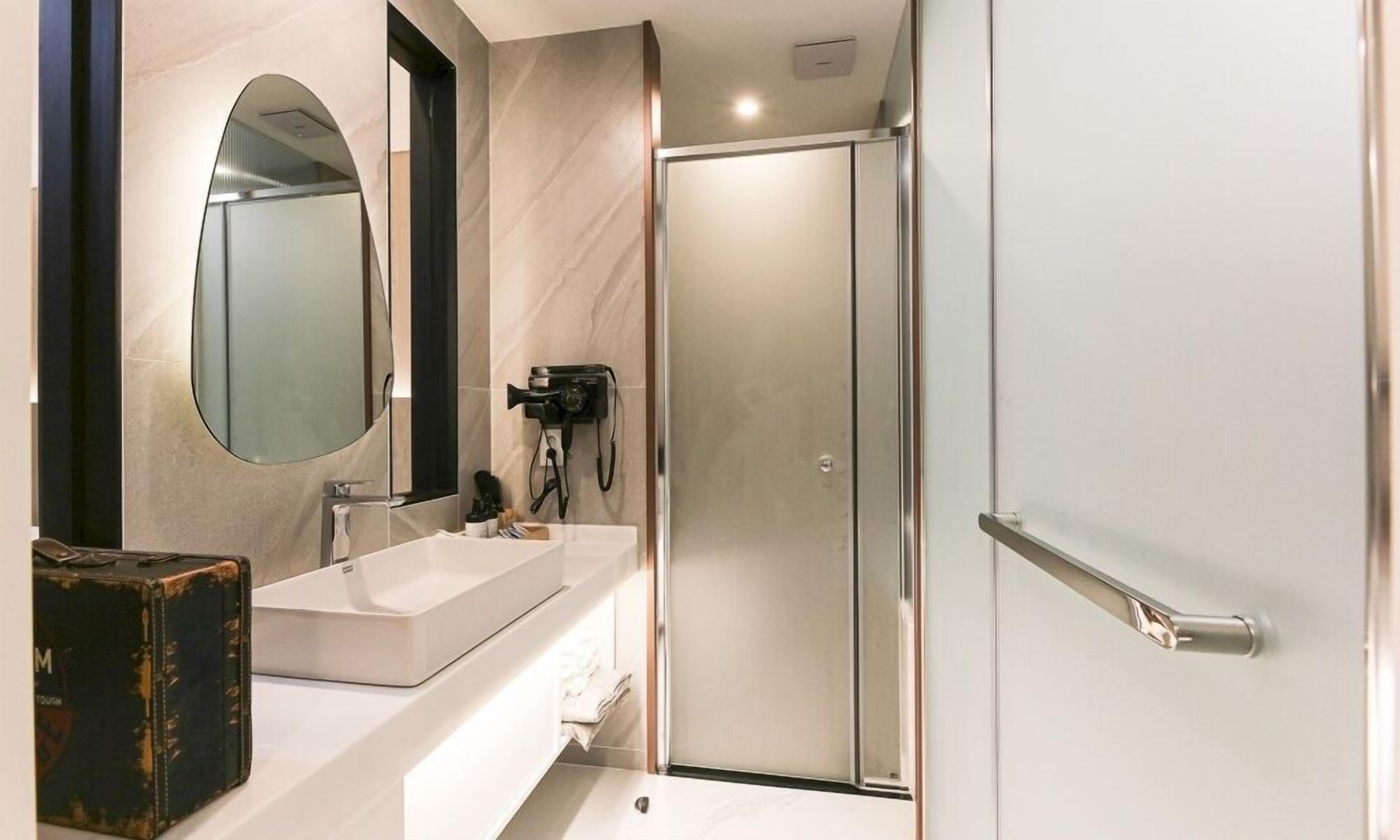 Een moderne badkamer met een grote spiegel, een wastafel en een douchehoek.