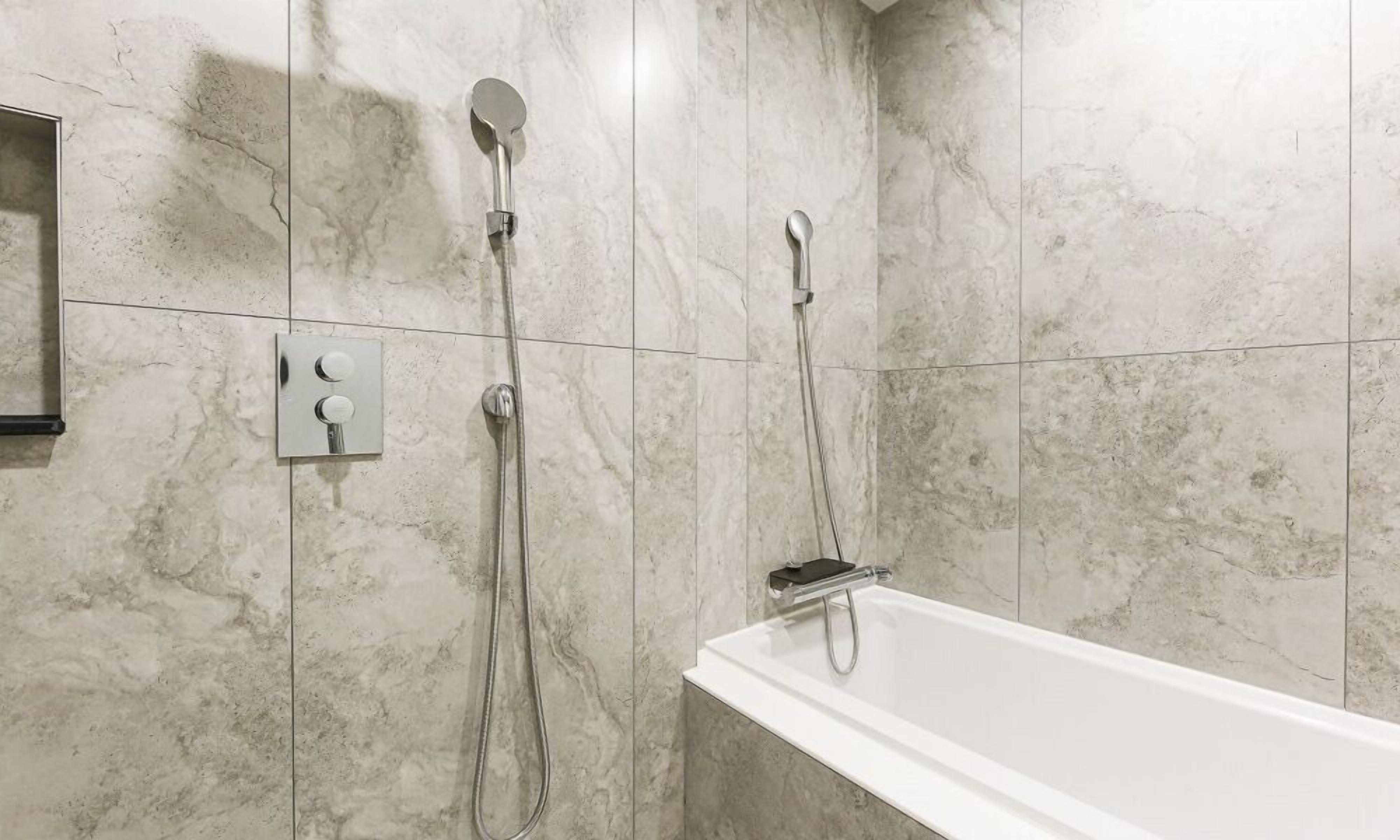 Un baño moderno con una bañera blanca, un cabezal de ducha de mano y un cabezal de ducha empotrado en la pared.