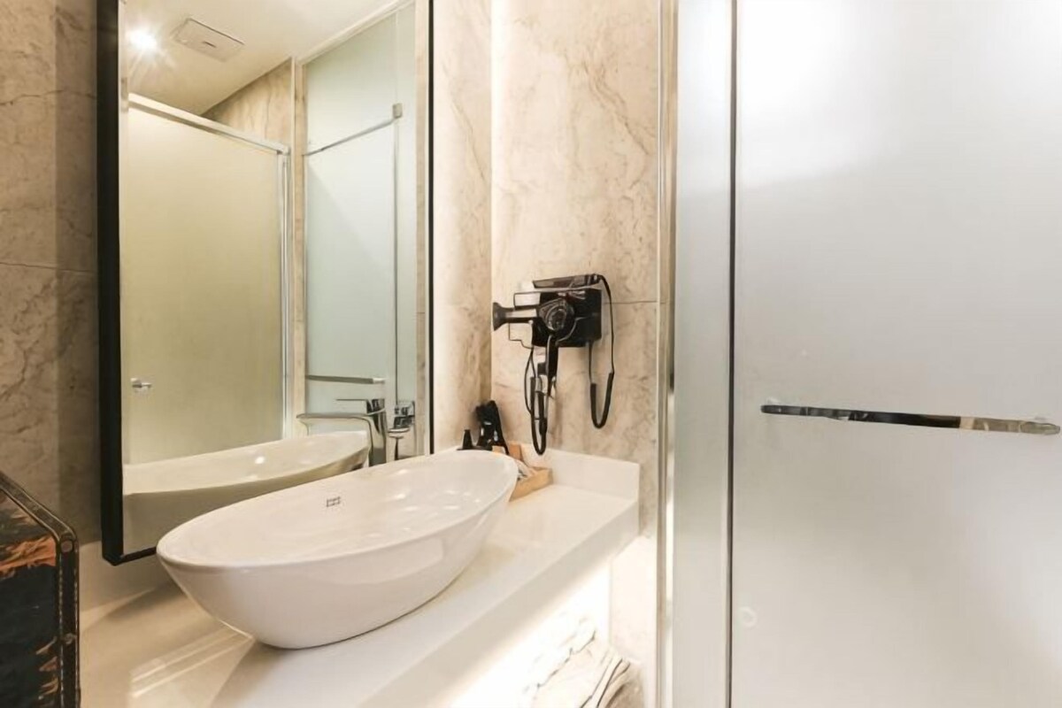 A bathroom with a large white sink, a mirror, and a handheld camera on the wall.