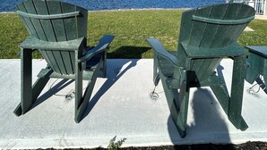 Two Adirondack chairs facing a body of water with a clear sky. - Cozy, Clean, Convenient and Spacious 3-bedroom apartment in beautiful Clayton. (Clayton)