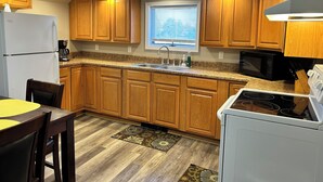 A compact kitchen with wooden cabinets, a built-in microwave, a refrigerator, and a dining area with a table and chairs. - Cozy, Clean, Convenient and Spacious 3-bedroom apartment in beautiful Clayton. (Clayton)