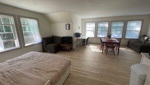 A spacious room with a bed, a sofa, a dining table with chairs, and a TV. - Blue Hill in the Woods (Blue Hill)
