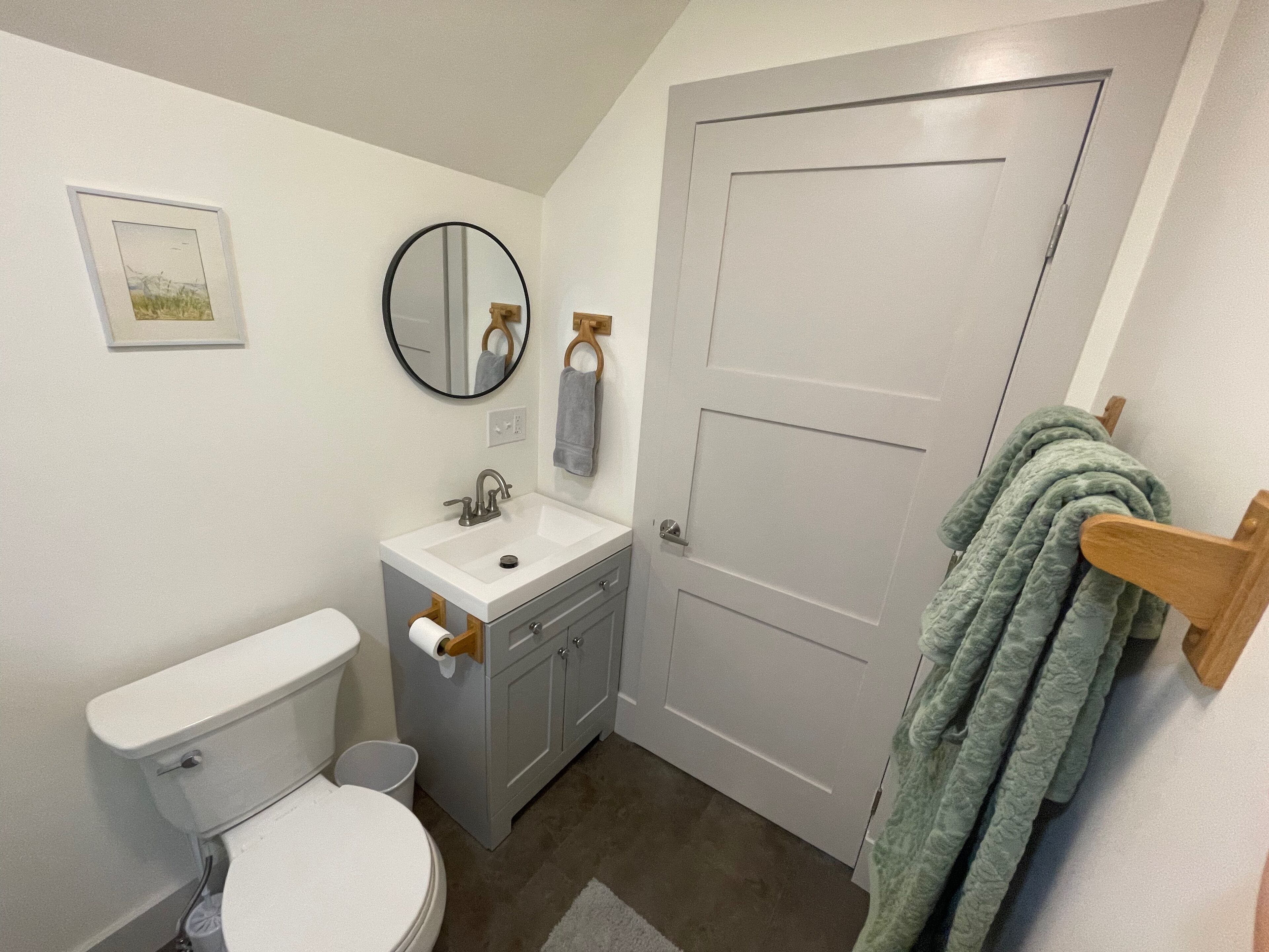 A bathroom with a toilet, sink, mirror, and a door.