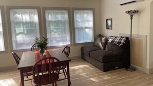 A room with a dining table, chairs, a sofa, and a floor lamp. - Blue Hill in the Woods (Blue Hill)