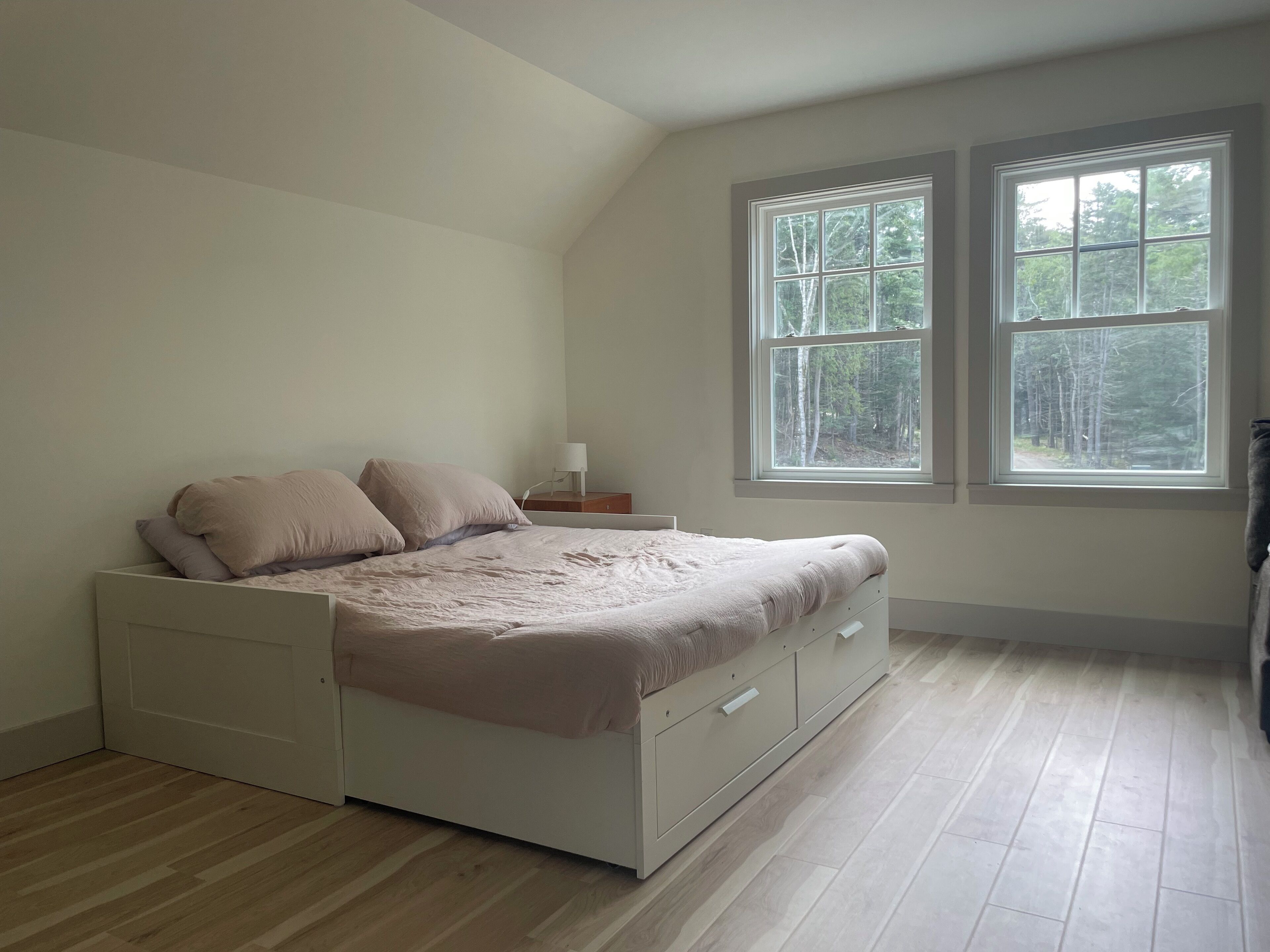Une chambre à coucher avec un lit, une table de chevet et deux fenêtres.
