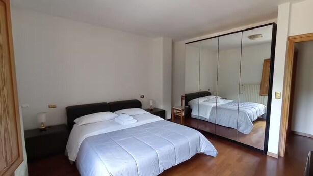 Habitación de hotel con una cama grande, una mesita de noche, un espejo y un armario.