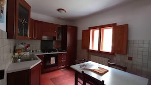 Una cocina con armarios de madera, un lavabo, una ventana y una mesa con tabla de cortar.