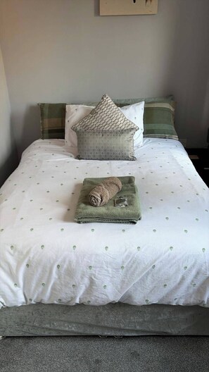 A neatly made bed with a patterned bedspread, a rolled towel, and decorative pillows. - 3 Bed, cozy and comfortable retreat (Spalding)