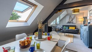 Un comedor con una mesa lista para el desayuno, un sofá y una cocina al fondo.