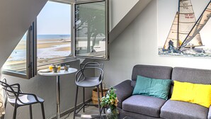 Una sala de estar moderna con vista al mar, un cuadro de un velero y una zona de estar acogedora.