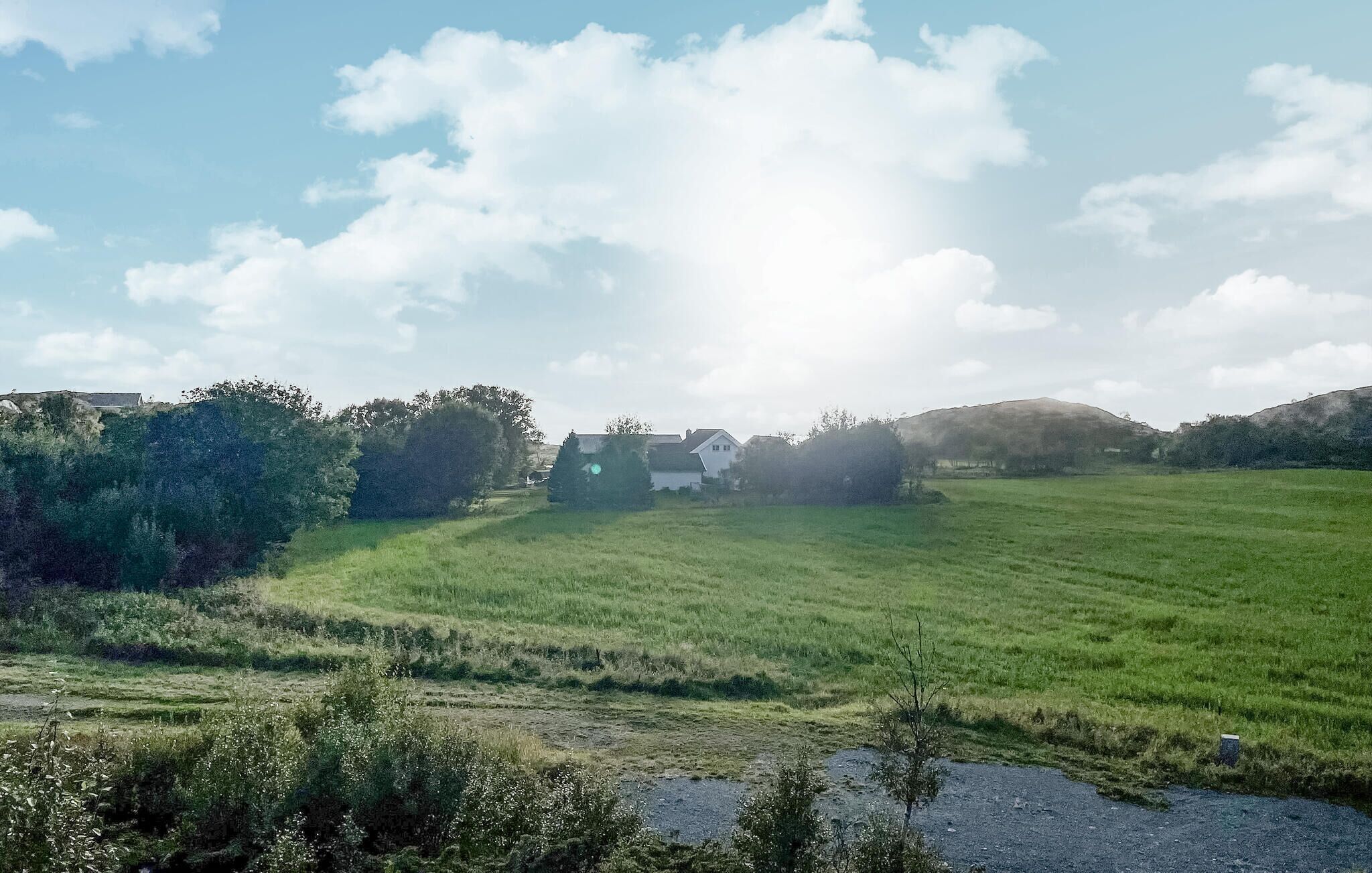 Un paisaje rural con una casa rodeada de campos verdes y árboles.