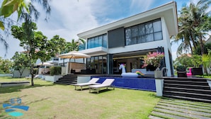 A modern house with a swimming pool, lounge chairs, and a unicorn statue.