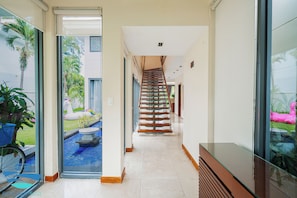 A modern interior with a glass door leading to a pool area, a staircase, and a reception desk.
