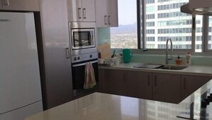 Une cuisine moderne dotée d’un grand îlot central, d’un four encastré et d’une fenêtre offrant une vue sur la ville.