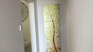 Un couloir doté d’un sol carrelé et d’une œuvre d’art fixée au mur, représentant un arbre.