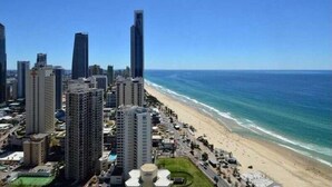 Un paysage urbain côtier avec de hauts immeubles, une plage et un ciel bleu dégagé.