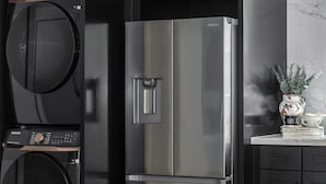 A modern kitchen with a built-in washer and refrigerator, dark cabinetry, and a marble backsplash.