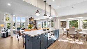 Una cocina moderna con una isla grande, iluminación colgante y vistas al exterior.