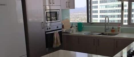 Una cocina moderna con una isla grande, horno empotrado y ventana con vista a la ciudad.